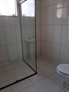瓜拉图巴Apartamentos na Quadra do Mar的一间带玻璃淋浴和卫生间的浴室