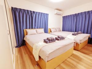 东京Rosenheim Tokyo Shinjuku Okubo的配有蓝色窗帘的客房内的两张床