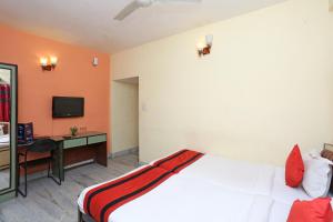 Ālīpur阿里波利旅馆的一间卧室配有一张床、一张书桌和一台电视