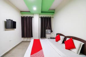 贾姆穆OYO Flagship 62748 Hotel Zeenat的一间卧室配有一张带红色枕头的床和一台电视。