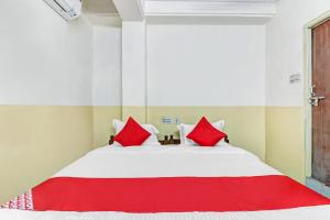 瓦朗加尔OYO Suraj Residency的一间卧室配有一张带红色枕头的大床