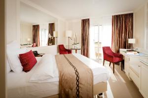 瓦杜兹Park Hotel Sonnenhof - Relais & Châteaux的酒店客房设有一张白色大床和红色椅子。