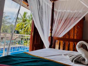 阿鲁特伽马Charly Villa的一间卧室设有一张天蓬床,享有游泳池的景色