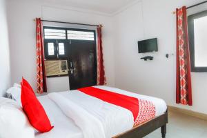 加济阿巴德OYO Hindon Residency的一间卧室配有一张带红色枕头的床和一扇窗户