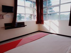 谏义里Rahayu Residence Syariah Kediri的卧室设有红色和白色的床和窗户。