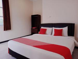 谏义里Rahayu Residence Syariah Kediri的一间卧室配有一张带红色枕头的大床