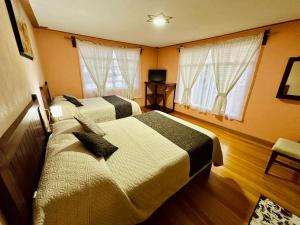 特拉尔普哈瓦Hotel Monarca Tlalpujahua的酒店客房带两张床和两个窗户