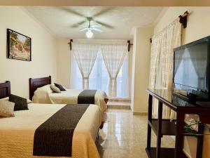 特拉尔普哈瓦Hotel Monarca Tlalpujahua的酒店客房设有两张床和一台平面电视。
