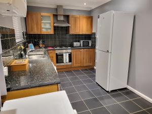 博勒姆伍德Garland Modern House With Parking & Garden的厨房配有白色冰箱和木制橱柜。