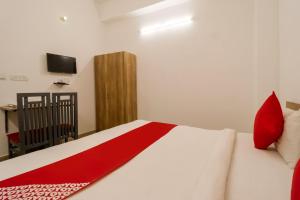 法里达巴德Perky Stay的一间卧室配有一张带红色枕头的床和电视。