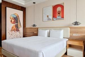 重庆重庆MontClassic精选酒店的卧室配有白色的床和墙上的绘画作品