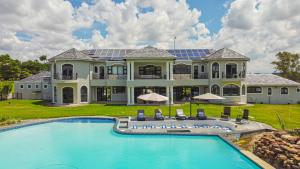 约翰内斯堡Villa Tasha Luxury Suites, Lanseria的一座大房子前面设有一个游泳池