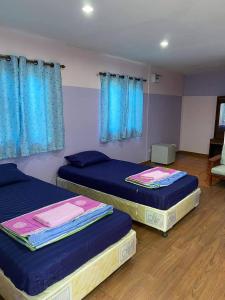 Ban Cha-omAmano green resort的配有蓝色窗帘的客房内的两张床