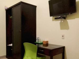 HalanganRedDoorz near Pantai Pandan Sibolga 2的客房设有书桌、电视和绿椅。