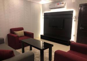 艾卜哈SNOW CLOUD的客厅配有平面电视和红色椅子。