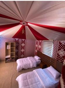 瓦迪拉姆Desert Life Camp的一间卧室设有两张床,拥有红色和白色的天花板