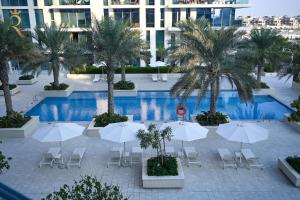 阿布扎比Sandy 1BR Soul Beach Mamsha Al Saadiyat Island的享有带遮阳伞和棕榈树的游泳池的顶部景致