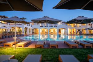 圣特雷莎加卢拉Mangia's Santa Teresa Sardinia, Curio Collection by Hilton的酒店设有带桌子和遮阳伞的游泳池
