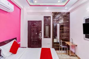 加济阿巴德Super OYO The Prima Residency的卧室设有粉红色的墙壁、一张床和一张书桌