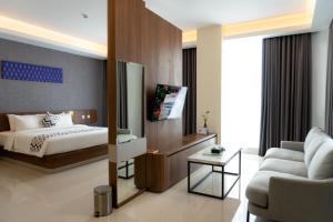 PatjinongongUNHAS HOTEL & CONVENTION的一间卧室配有一张床、一张沙发和一台电视。
