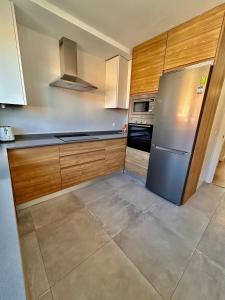 马德里Moderno apartamento inteligente的厨房配有木制橱柜和不锈钢冰箱。