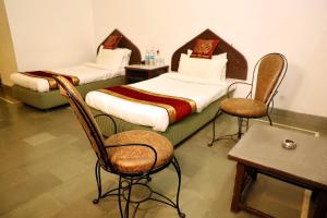 RājgarhPanna Tiger Resort- Riverside Property的配有两张床铺的房间,配有椅子和桌子