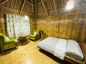 BulusanBirbeck Lodge的一间卧室配有一张床、两把椅子和一张桌子