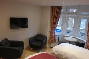 伦敦The Alma Rooms的一间卧室配有一张床、一把椅子和电视