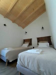 阿尔奇瓦Alqueive GUEST HOUSE的配有白色墙壁和木制天花板的客房内的两张床