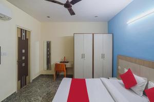 古尔冈Capital O Hotel Crown Inn Near Appu Ghar的一间卧室配有一张带红色枕头的床和一张桌子