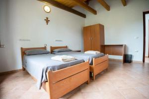 LàconiOASI FRANCESCANA SANT'IGNAZIO DA LACONI的卧室设有两张床,墙上有十字架