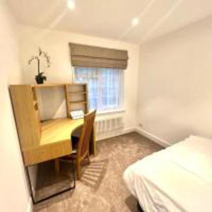 亨顿Inviting 4-Bed House in Finchley London的一间卧室配有一张桌子、一张床、一张桌子和一个窗户。