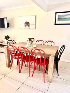 杰斯蒙Maya Newcasle 6 bedrooms home的餐桌周围摆放着红色椅子