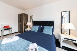 雷丁Well Equipped Apartment for Relocators and Contractors的一间卧室配有一张蓝色的床、两张桌子和两盏灯。