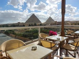 开罗DouDou Pyramids View Hotel的阳台配有桌椅和金字塔。