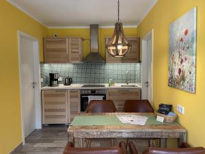 措森Ferienhaus Eichhörnchen的厨房设有黄色的墙壁和桌椅
