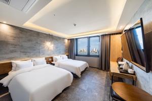 束草市Sokcho Business Hotel CAMEL的配有大窗户的酒店客房内的两张床