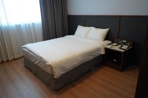 泗川泗川格旅游大酒店的一间卧室配有一张大床和床头柜