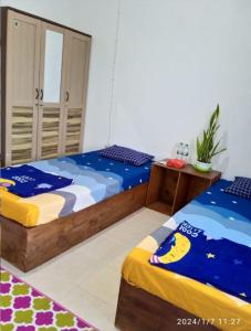 SintangWismaALAS Syariah Guesthouse的一间卧室设有两张床和床头柜