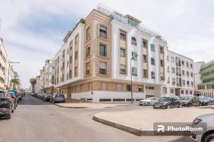 拉巴特Appartement Rabat Agdal City Centre - SwiftStay的一条城市街道上一座大型建筑,有停放的汽车