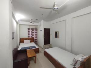 达卡New Hotel Labbaik的一间卧室配有两张床和吊扇