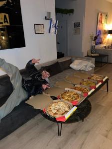 特拉维夫Ofek's place - Midtown TLV的躺在沙发上的人,上面有盒子比萨饼
