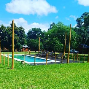 伊瓜苏港Cabañas El Despertar的公园里的一个游泳池,有长椅和草地