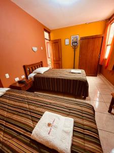 特鲁希略Hostal El Pillkay的黄色墙壁客房的两张床