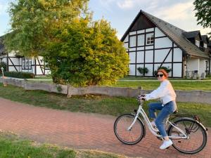 普劳西Landhotel Rose am Plauer See garni的一位在房子前面骑着自行车的女人