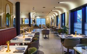 海斯Courtyard by Marriott London Heathrow Airport的餐厅设有桌椅和窗户。