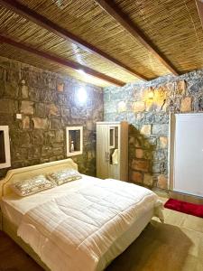MisfāhJebel shams Sky的卧室配有一张石墙内的大床