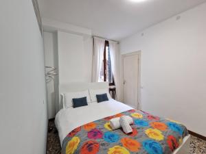 威尼斯Veneziacentopercento Apartments & Rooms的一间卧室配有一张大床和色彩缤纷的毯子