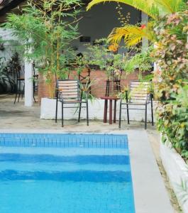 西哈努克Manoha Villa的一个带两把椅子、一张桌子和一张桌子及椅子的游泳池