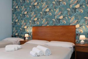 毕博纳的码头Hotel Riva Etrusca的一张带花卉壁纸的客房内的两张床
